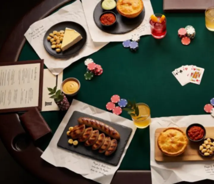 Shared platters and drinks arranged beside a poker table in a restaurant card lounge